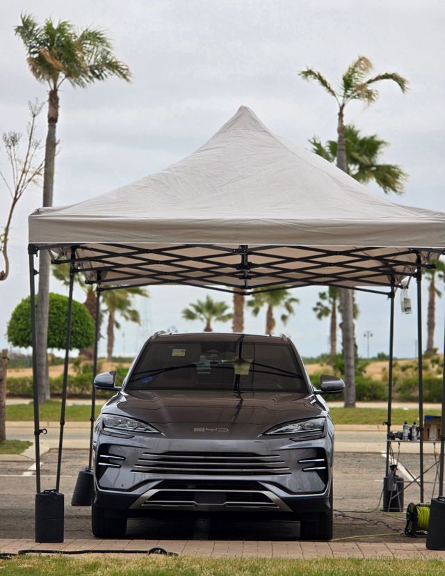 A BYD SUV under the gazebo, set up among palm trees