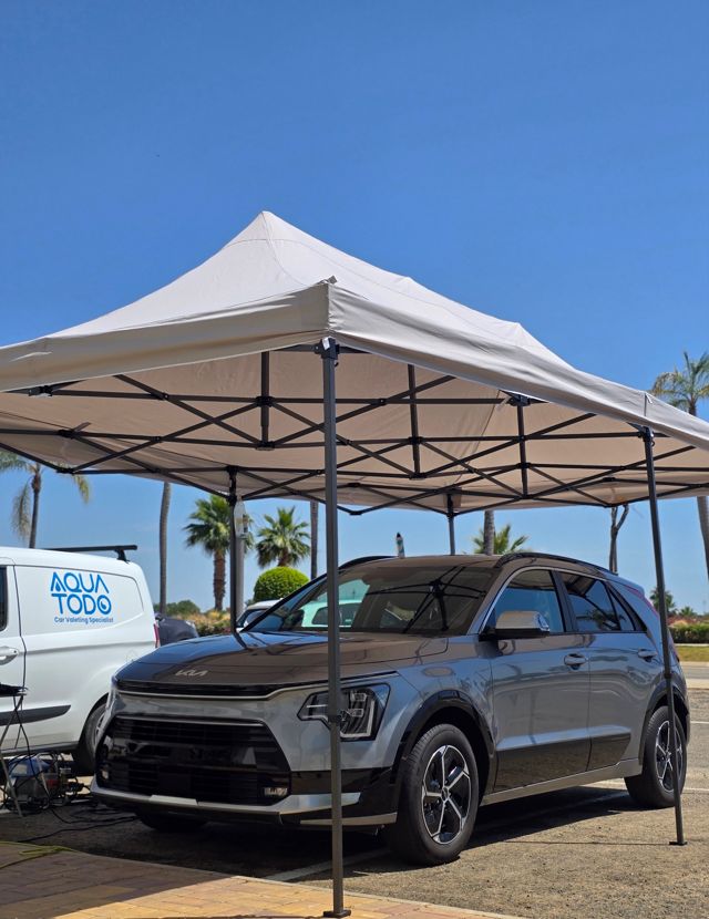 A Kia Niro under the Aqua Todo gazebo, with the van alongside