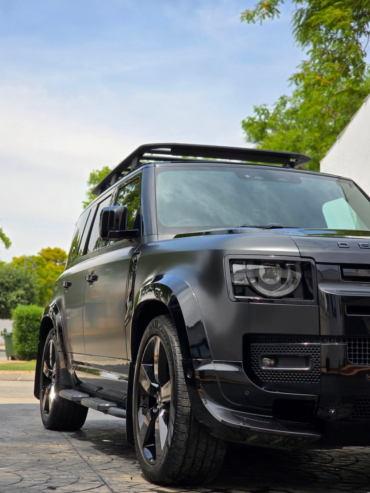 Land Rover Defender negro recién limpiado en la entrada de una villa